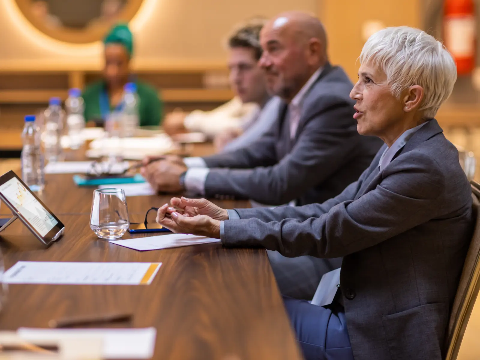 A professional meeting scene with a diverse group of people seated at a long table, actively engaging and sharing ideas.