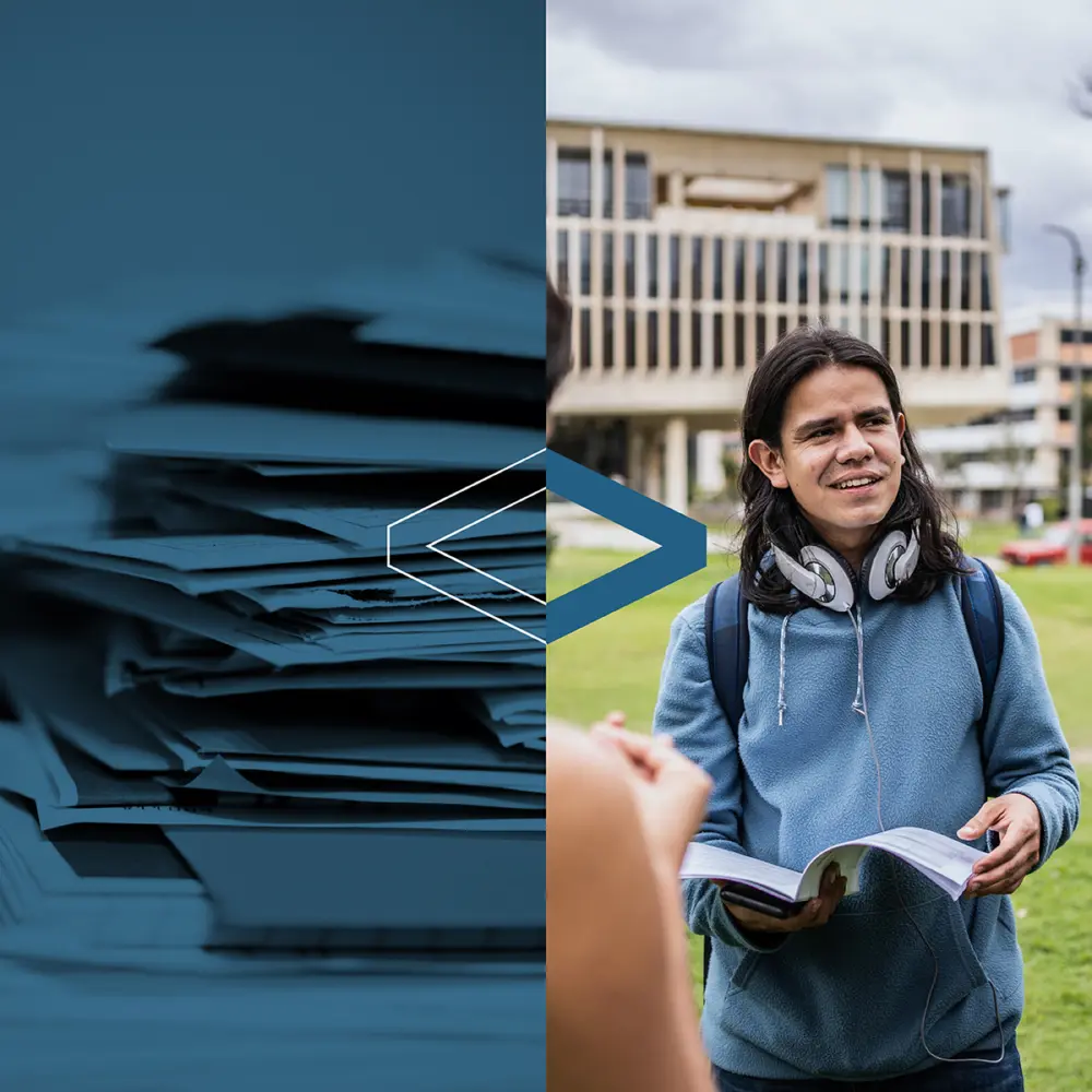 A young person with long hair and headphones smiles while holding a book outdoors, with a blurred stack of papers on one side.