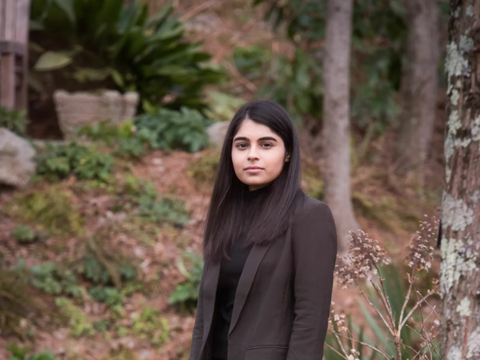 The subject of the story Sneha Dave stands in a wooded area looking directly at the camera.