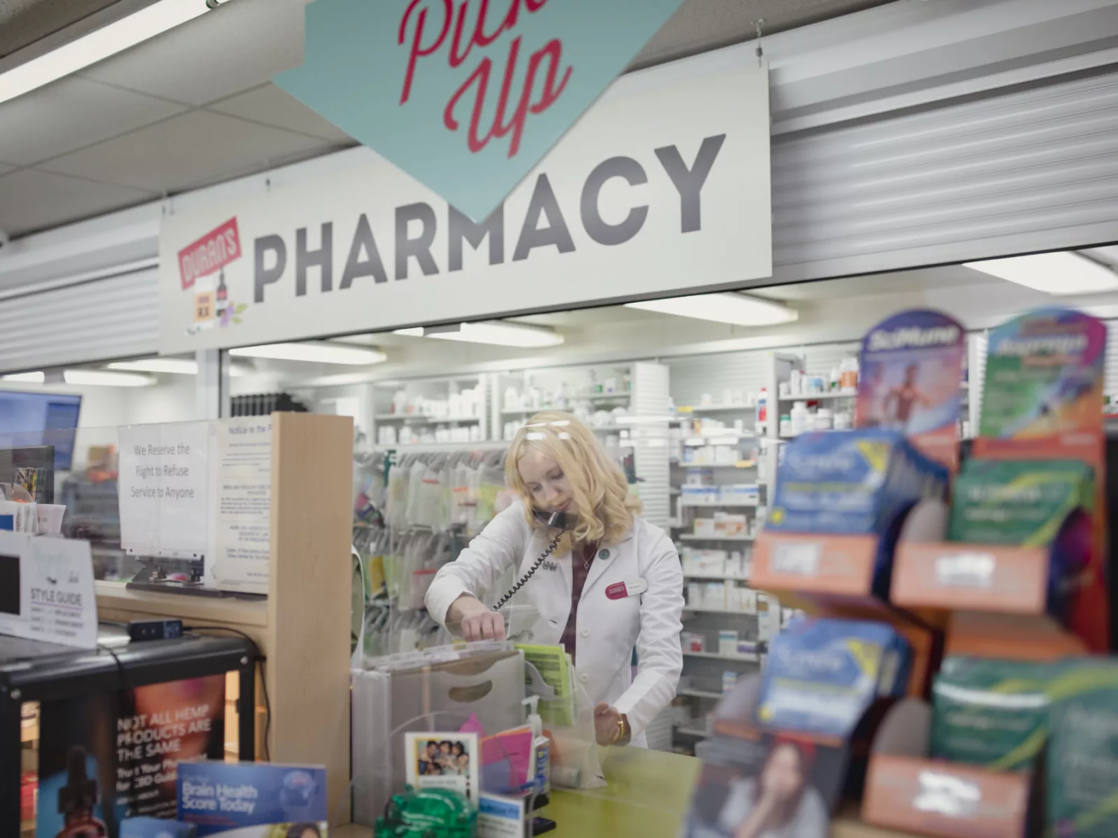Pharmacist is seen behind the pharmacy window filling prescriptions.
