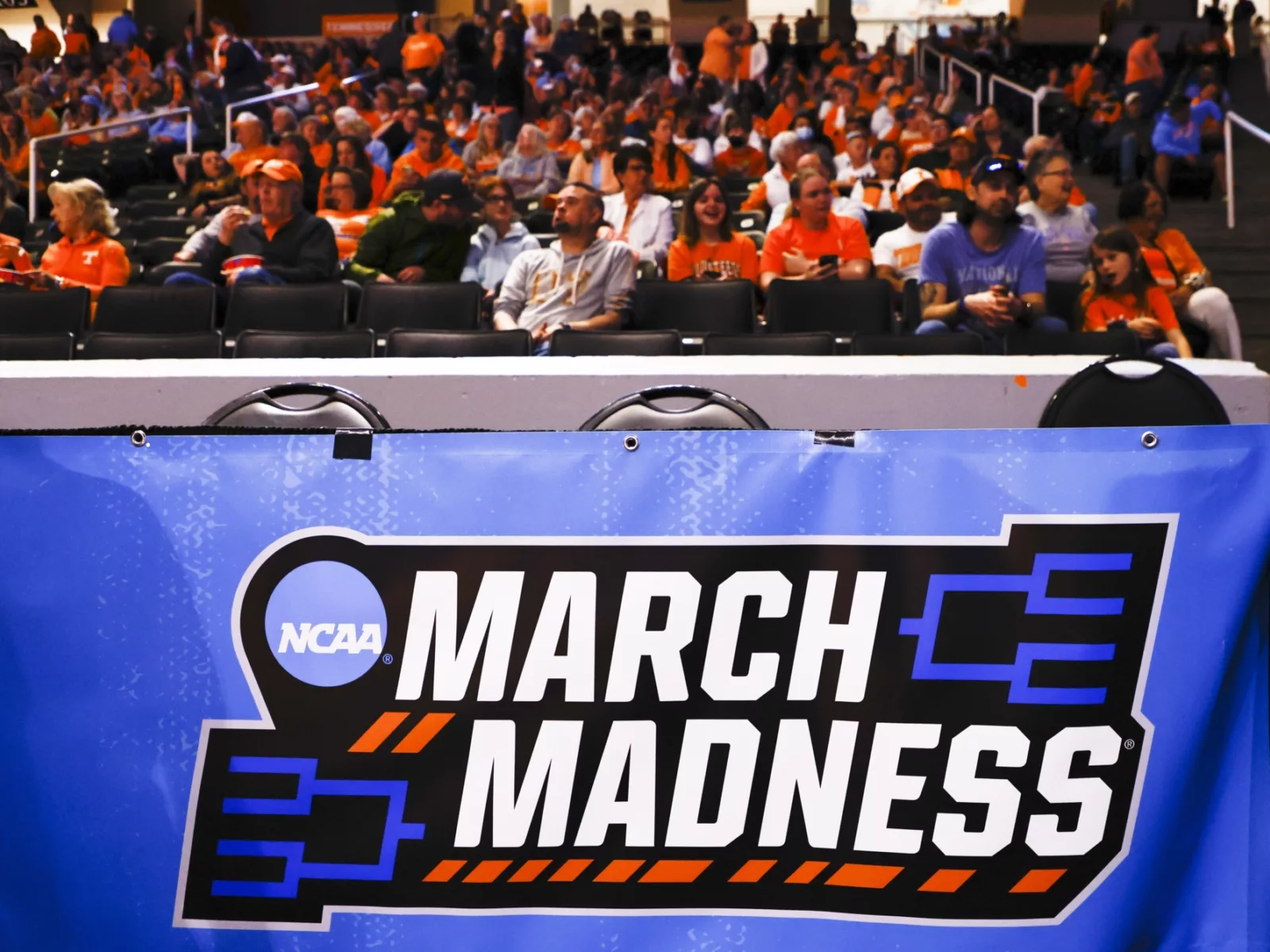 A March Madness banner is seen in front of the stands as fans watch a game.