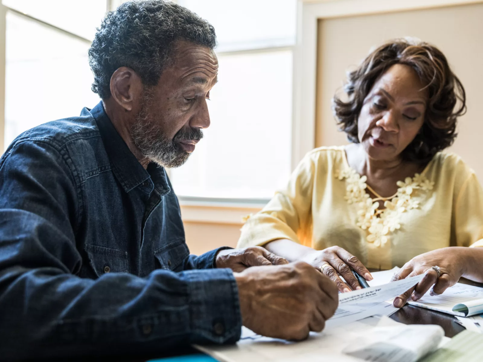 Couple sits at kitchen table looking over documents.