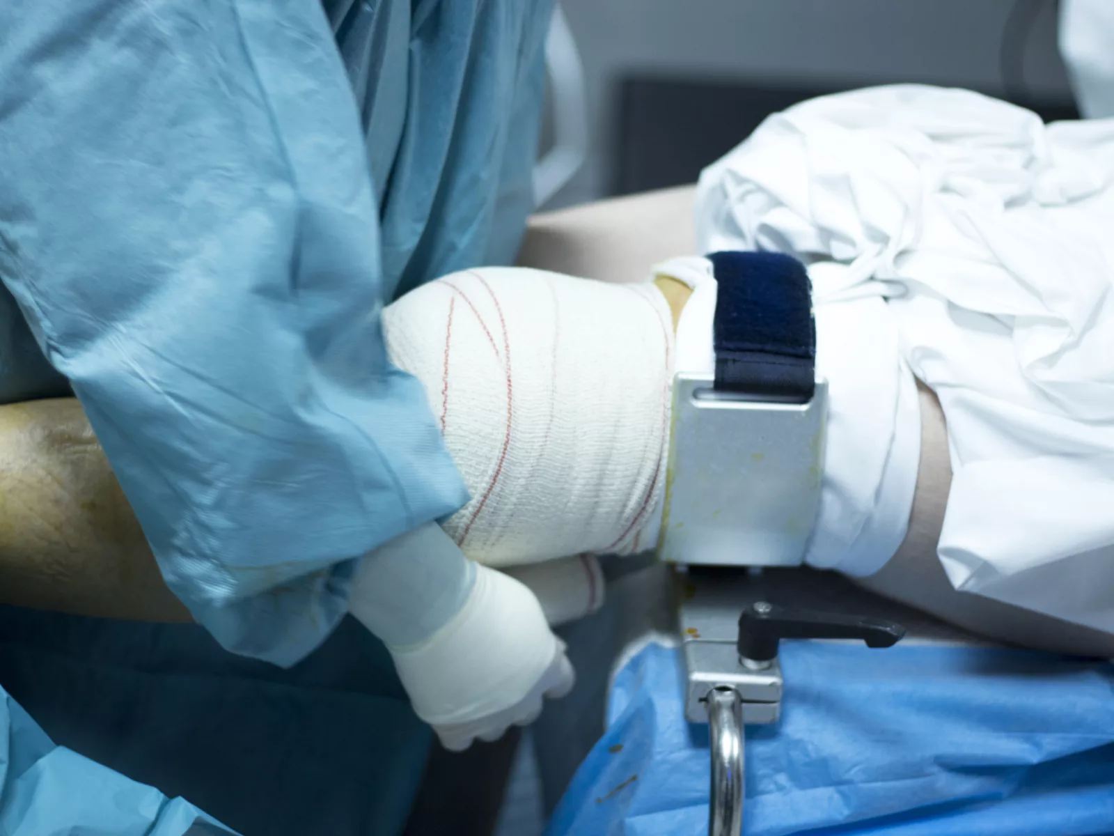 Doctor in hospital wraps a patient's knee after surgery.