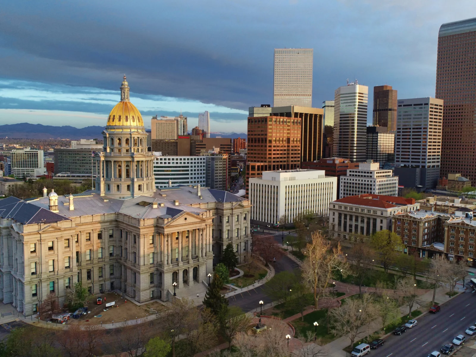 The Colorado State Capitol with its distinctive golden dome stands proudly in the foreground, surrounded by Denver's modern skyline.