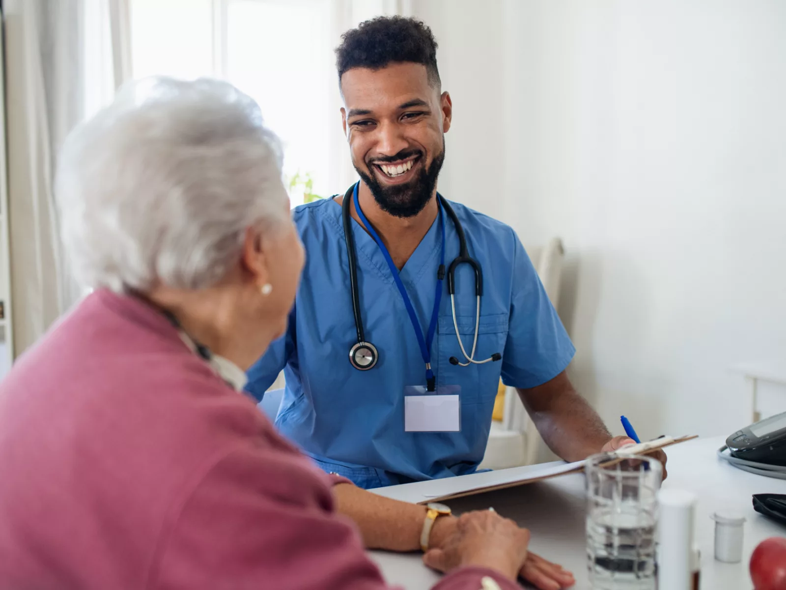 Healthcare worker visits senior woman indoors at home.