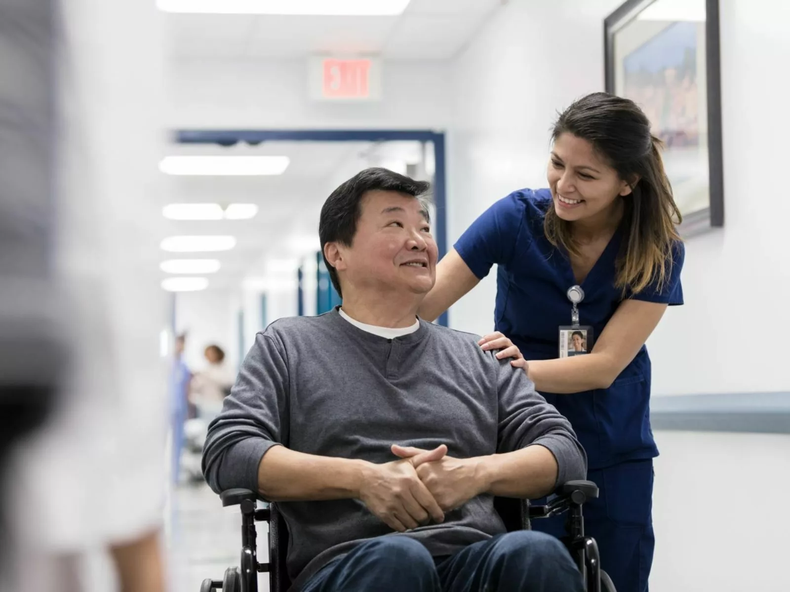 Female care provider speaking with disabled male patient in wheel chair.